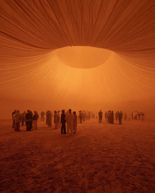 A crowd in motion beneath an ember-coloured fabric canopy