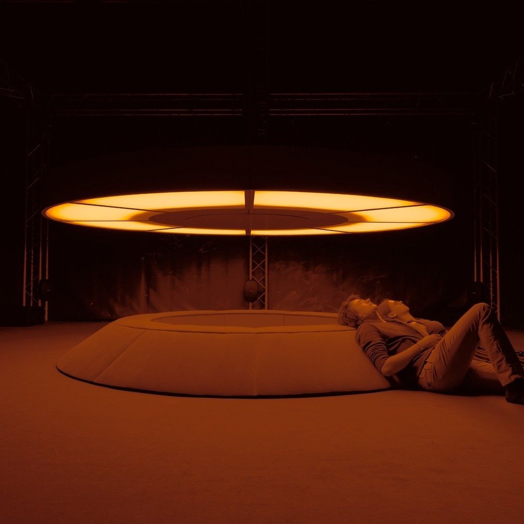 A reclining figure under a suspended ring of light