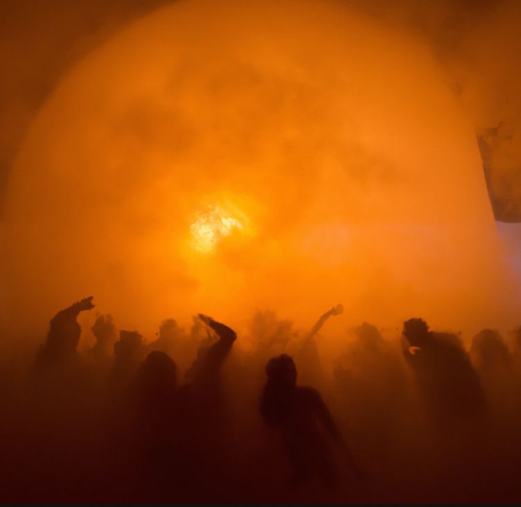 A dancing crowd in haze under a great sun-disc